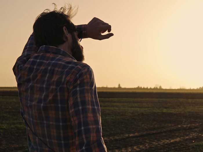 Farmer looks over fields, concerned about soil health. iStock.com/undefined