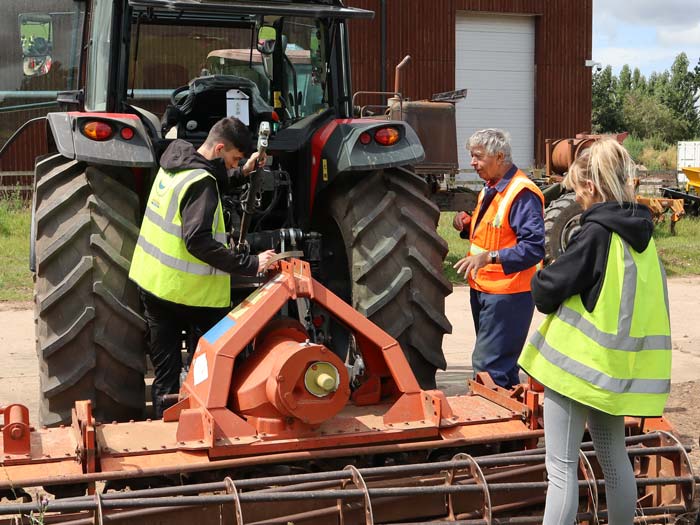 Roger Madge guides to young farmers on how to connect equipment to a tractor during a training session at Harper Adams University on July 7, 2023.