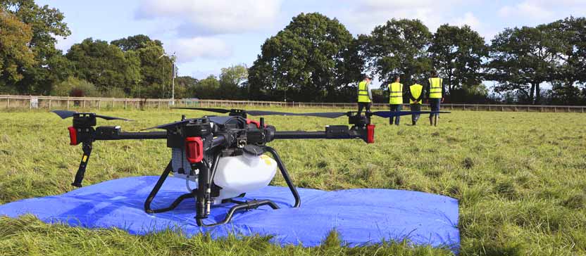 Three farmers walk a field with instructor Scott Dowell, of Autospray Systems, on a drone training course at Harper Adams University.