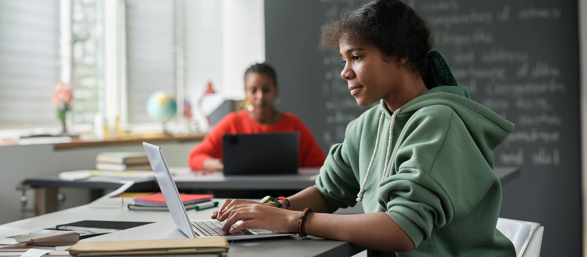 Student learning on her laptop in a classroom environment.